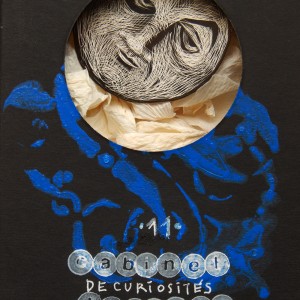 S É R I E “ C A B I N E T -D E C U R I O S I T É S- L U N A I R E ”. Série de 15 boîtes avec fenêtres en verre renfermant des lunes réalisées en carte à gratter. Dimensions des boîtes : L10,5 cm x H 27,5 cm x P 3,5 cm Boîte n° 11 – La lune pleine et… désabusée